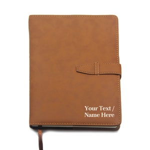 May include: A brown faux leather journal with a strap closure and a personalized inscription that reads "Your Text / Name Here".