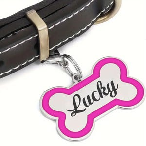 May include: A pink bone-shaped dog tag with a silver border and the name "Lucky" written in black.