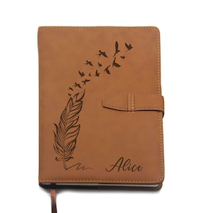 May include: A brown leather journal with a feather and birds design. The journal has a strap closure and the name "Alice" is printed on the cover. The journal has a ribbon bookmark.