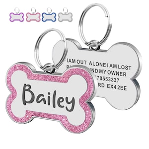 May include: Bone-shaped pet ID tags with a silver finish and pink glitter trim. One tag displays the name "Bailey" in gray lettering. The other tag has contact information. Additional tags in purple, pink, blue, and silver are visible.