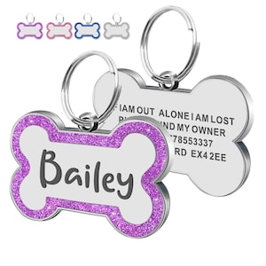 Op de afbeelding: Hondenpenning in de vorm van een bot met een paarse glitterrand en de naam "Bailey" in zwart. De penning is zilverkleurig met een ring om te bevestigen. De achterkant van de penning bevat contactgegevens.