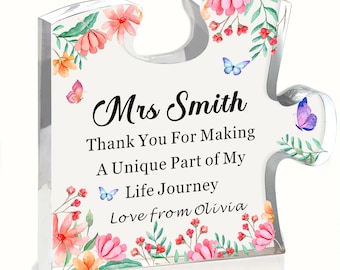 May include: A clear acrylic puzzle piece with floral and butterfly accents. The text reads "Mrs Smith Thank You For Making A Unique Part of My Life Journey Love from Olivia."