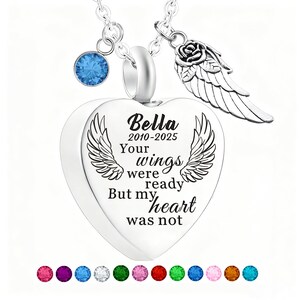 May include: A silver heart-shaped pendant necklace with the inscription "Bella 2010-2025 Your wings were ready But my heart was not." The necklace includes a blue gemstone, a rose and wing charm, and a selection of colorful gemstones at the bottom.