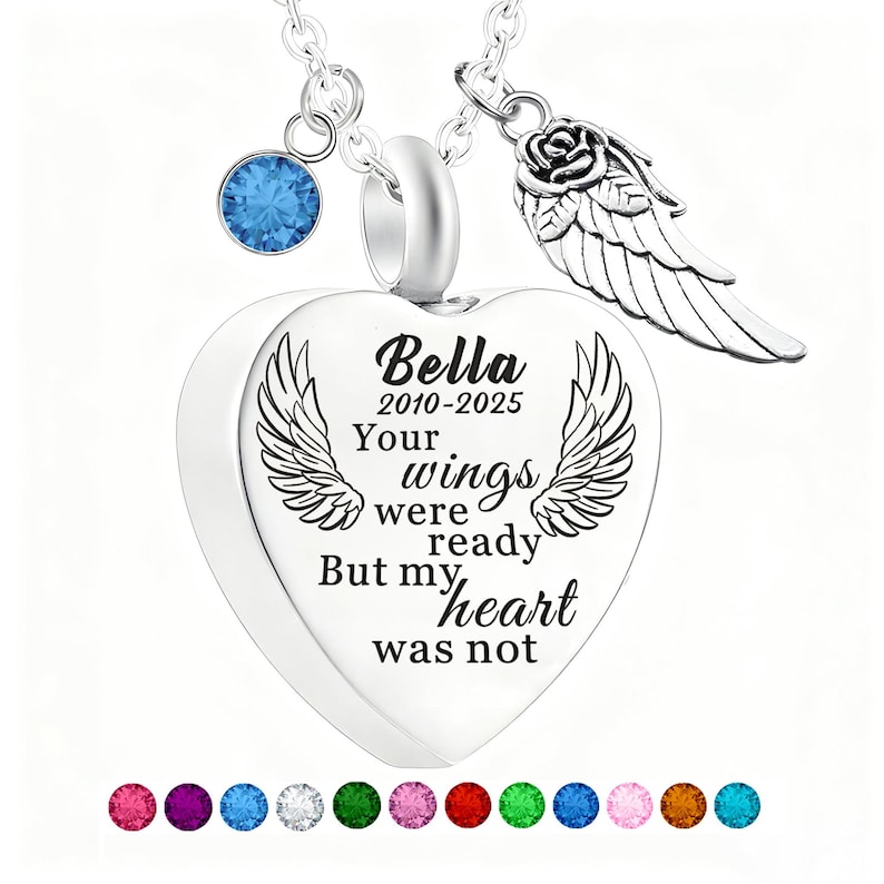 May include: A silver heart-shaped pendant necklace with the inscription "Bella 2010-2025 Your wings were ready But my heart was not." The necklace includes a blue gemstone, a rose and wing charm, and a selection of colorful gemstones at the bottom.