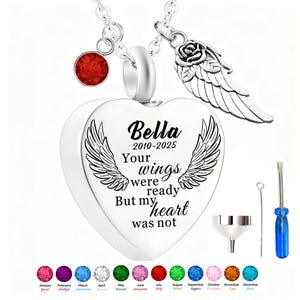 May include: A silver heart-shaped pendant necklace with engraved wings and the text "Bella 2010-2025 Your wings were ready But my heart was not." Includes a red gemstone, a rose and wing charm, and a set of tools.