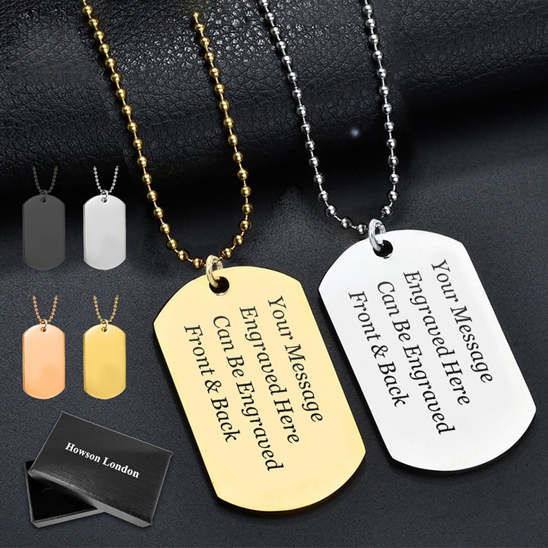 May include: Two silver dog tag necklaces with a gold dog tag necklace. The dog tags are engraved with the text "Your Message Engraved Here Can Be Engraved Front & Back". The necklaces are displayed on a black background with a black box that says "Howson London".