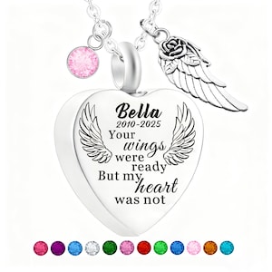 May include: A silver heart-shaped pendant necklace with the inscription "Bella 2010-2025 Your wings were ready But my heart was not." The necklace includes a pink gemstone charm, a rose and wing charm, and a selection of colorful gemstones at the bottom.