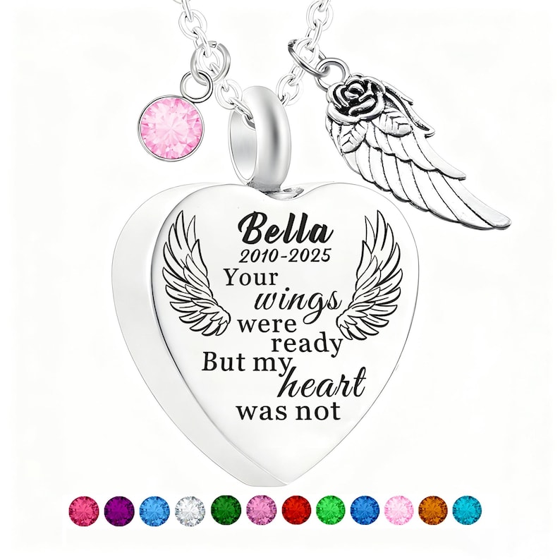May include: A silver heart-shaped pendant necklace with the inscription "Bella 2010-2025 Your wings were ready But my heart was not." The necklace includes a pink gemstone charm, a rose and wing charm, and a selection of colorful gemstones at the bottom.