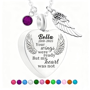 May include: A silver heart-shaped pendant necklace with the inscription "Bella 2010-2025 Your wings were ready But my heart was not." Features a purple gemstone and a rose with wing charm. A memorial jewelry piece.