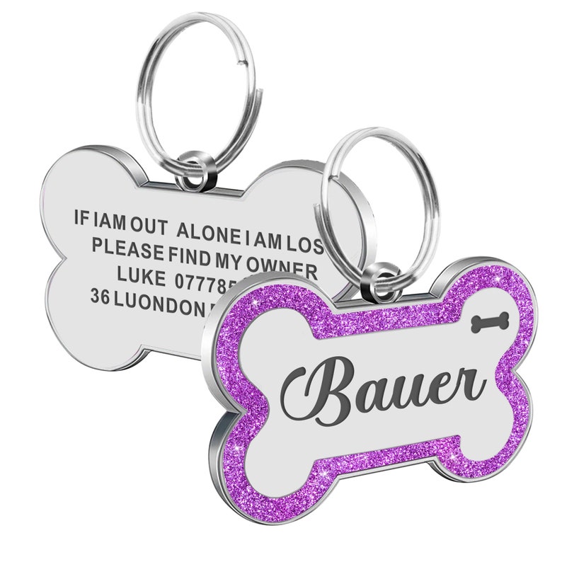 May include: A silver bone-shaped dog tag with a purple glitter border. The tag has the text "IF I AM OUT ALONE I AM LOST PLEASE FIND MY OWNER LUKE 077785 36 LUONDON" on one side and the name "Bauer" on the other side.