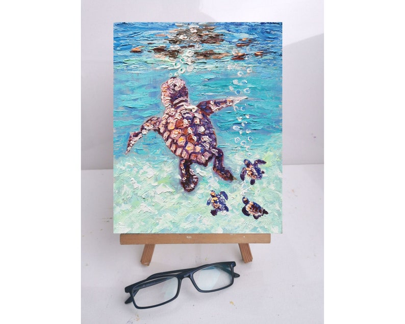 May include: A painting of a sea turtle and her babies swimming in the ocean. The mother turtle is brown and has a light blue background. The baby turtles are smaller and have a darker blue background.