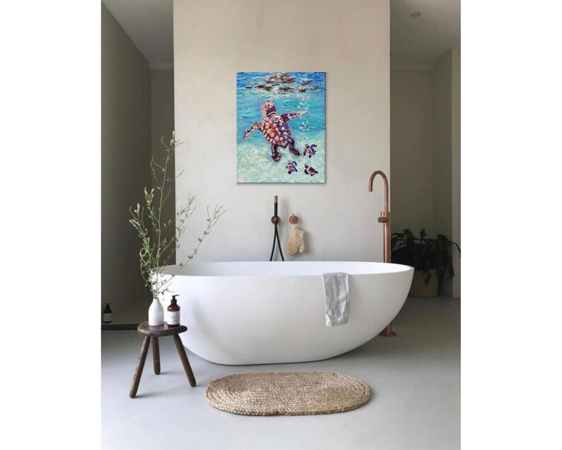May include: A painting of a sea turtle swimming in the ocean with three smaller turtles following behind. The painting is in a bathroom setting with a white bathtub and a copper faucet.