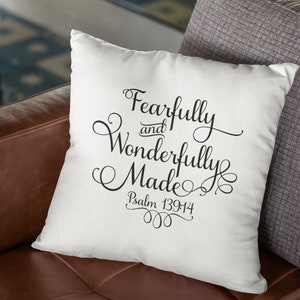May include: White throw pillow with black text that reads "Fearfully and Wonderfully Made" with the verse "Psalm 139:14" underneath. The pillow is sitting on a brown leather couch.