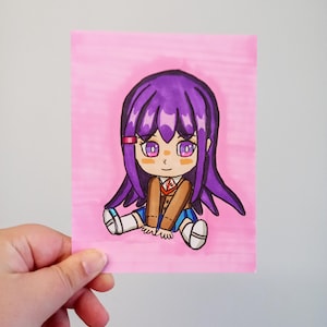 Peut inclure: Illustration dessinée à la main d'un personnage de style chibi aux cheveux violets, portant une veste marron, une jupe bleue et des chaussettes blanches. Le personnage est assis sur un fond rose. L'œuvre est sur un morceau de papier rectangulaire.