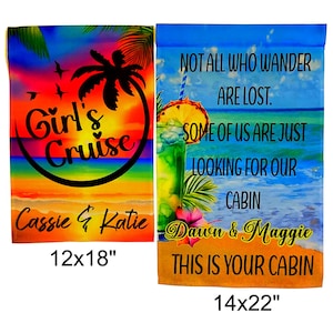 May include: Two colorful garden flags with tropical beach scenes and text. The first flag is a sunset scene with the text "Girl's Cruise" and "Cassie & Katie" with a 12x18 inch measurement. The second flag is a beach scene with a drink and the text "Not all who wander are lost. Some of us are just looking for our cabin. Dawn & Maggie This is your cabin" with a 14x22 inch measurement.