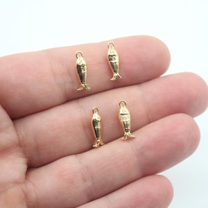 Peut inclure: Quatre breloques de poisson dorées avec une boucle en haut pour les attacher à des bijoux ou d'autres objets artisanaux.
