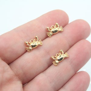 Peut inclure: Trois breloques en forme de crabe dorées avec une boucle pour les attacher à des bijoux ou d'autres objets artisanaux.