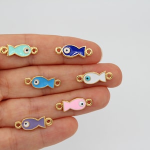 May include: Assortment of six gold-toned fish charms with blue, white, pink, and purple enamel and a blue evil eye detail. The charms have jump rings for attaching to jewellery.