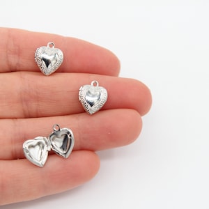 Può includere: Tre ciondoli a forma di cuore argentati con disegni intricati. I ciondoli hanno un'apertura a cerniera e sono perfetti da aggiungere a collane o braccialetti.