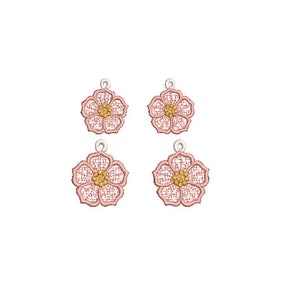 Puede incluir: Cuatro pendientes de color rosa en forma de flor con un centro dorado. Los pendientes son delicados y tienen un diseño de encaje.