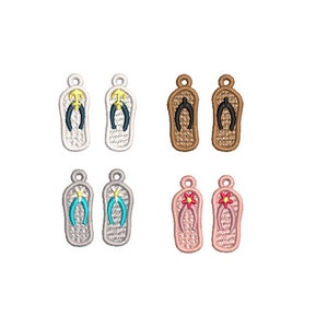 May include: Set of eight embroidered flip-flop charms in four different colors: white, brown, gray, and pink. Each charm features a different design, including an anchor, a flower, and a simple strap.