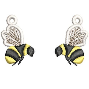 May include: Two embroidered bee-shaped charms. Each bee has a black and yellow striped body, black head, and detailed wings. The wings are a light tan color. The charms have a small loop at the top for hanging.