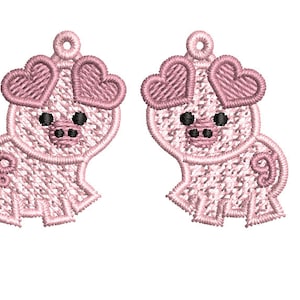 以下が含まれることがあります： ハート型の目をしたピンクのブタのイヤリングのペア。ブタは詳細なデザインで刺繍されています。