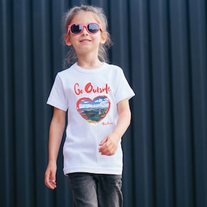 May include: White t-shirt with a red heart graphic that says "Go Outside" and has a picture of a lake and mountains inside the heart. The text "Go Green" is written below the heart.