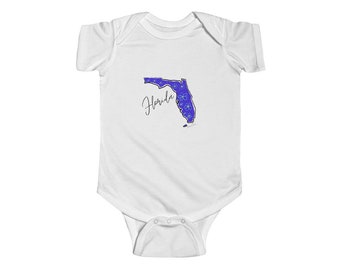 Könnte beinhalten: Weißer Baby-Strampler mit einer blauen Umrandung des Bundesstaates Florida mit weißen Blumen im Inneren. Das Wort "Florida" ist in Kursivschrift unter dem Bundesstaat geschrieben.
