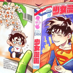 Puede incluir: Primer plano de un cómic con una portada colorida que presenta a un joven con un traje de superhéroe rojo y azul. El cómic se titula "少女漫画" y la portada presenta el texto "JON DAMI" y "10".