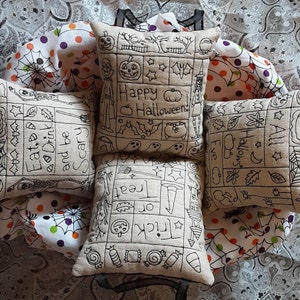 May include: Four square Halloween-themed throw pillows with black embroidered designs and text. The pillows feature various Halloween motifs, including pumpkins, ghosts, and spiderwebs. The text includes phrases like "Happy Halloween" and "Eat, Drink, and be Scary".