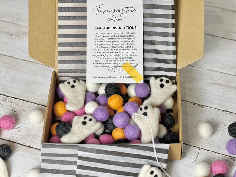 K&ouml;nnte beinhalten: Ein Halloween-Bastelset in einer offenen Pappschachtel. Das Set enth&auml;lt wei&szlig;e Filzgespenster, bunte Filzkugeln in Rosa, Lila, Orange, Schwarz und Wei&szlig; sowie eine Anleitung. Auf der Karte steht "This is going to be so fun!"