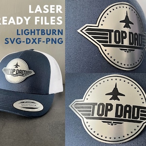 Könnte beinhalten: Eine blaue und weiße Trucker-Kappe mit einem silbernen Metallabzeichen, auf dem "Top Dad" mit einem Düsenflugzeug-Design steht. Das Abzeichen ist von einem Kreis aus Sternen umgeben.