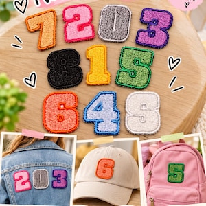 May include: A collection of iron-on number patches in various colours including orange, pink, grey, purple, black, yellow, green, blue, and white. The patches feature embroidered edges and are shown applied to a denim jacket, a beige cap, and a pink backpack.