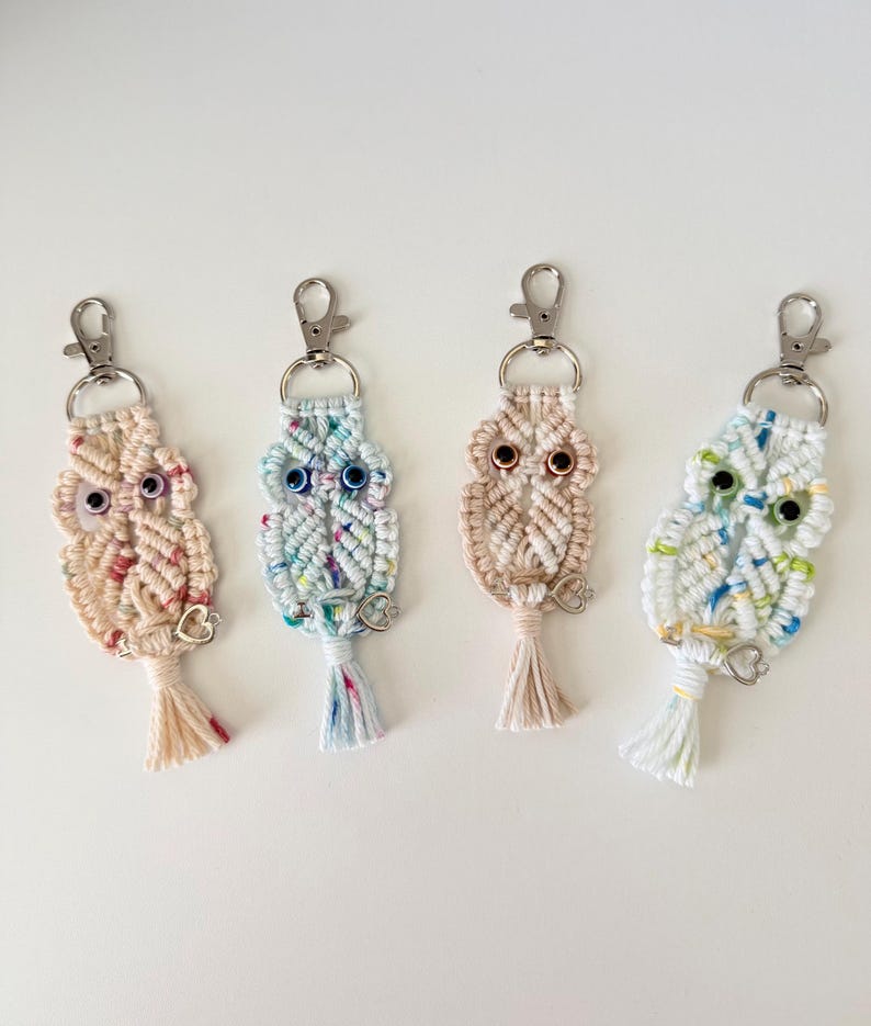 May include: Four macrame owl keychains in pastel colors. Each owl has a silver-tone clasp, bead eyes, and a small tassel. The owls are in shades of pink, blue, and beige, with a white background.