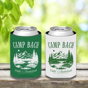 May include: Two green and white insulated beverage holders with a mountain scene and the text "Camp Bach" and "Callie's Bachelorette Lake Tahoe, California".