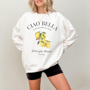 Könnte beinhalten: Weißer Pullover mit einem Zitronenmotiv und dem Text "CIAO BELLA La vita è più dolce con i limoni Dolce far Niento Sicilia. Italia"