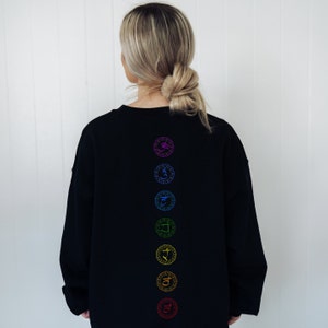 May include: Black sweatshirt with a vertical row of seven colorful chakra symbols on the back.