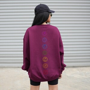 May include: A maroon sweatshirt with a vertical row of seven colorful chakra symbols printed on the back.