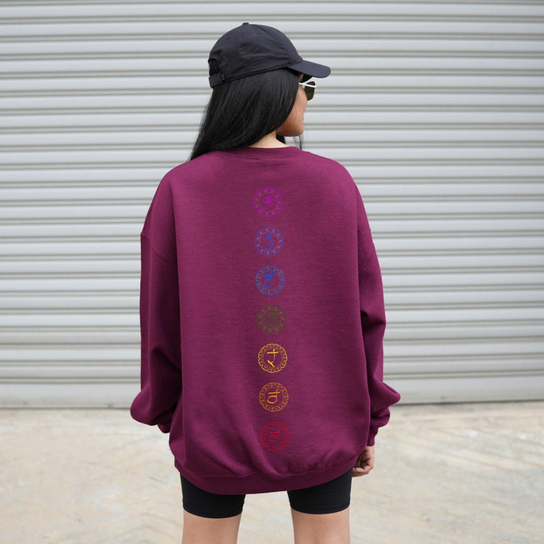 May include: A maroon sweatshirt with a vertical row of seven colorful chakra symbols printed on the back.