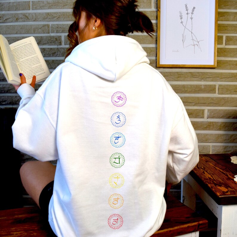 May include: White hooded sweatshirt with a rainbow colored chakra symbols printed on the back. The symbols are in a vertical line and include Om, Svadhisthana, Manipura, Anahata, Vishuddha, Ajna, and Muladhara.