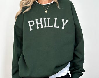 May include: A dark green sweatshirt with the word "PHILLY" printed in white on the front.