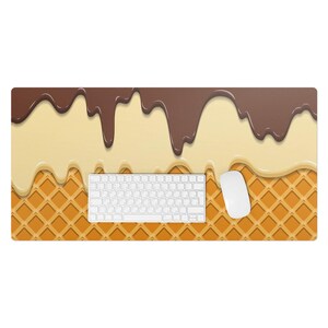 May include: A brown and white waffle-patterned desk mat with a white keyboard and mouse. The mat has a design of melted chocolate and vanilla ice cream.