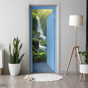 Op de afbeelding: Een blauwe deur opent zich naar een weelderig groen bos met een waterval die er doorheen stroomt. De deur is geplaatst tegen een witte muur met een plant in een pot en een lamp.