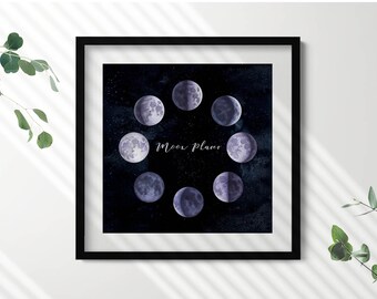 Può includere: Una stampa incorniciata nera con uno sfondo blu scuro che presenta un'illustrazione ad acquerello di otto diverse fasi lunari. Il testo "Moon Phases" è scritto in lettere corsive bianche.