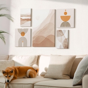 May include: A set of five abstract wall art pieces in neutral tones of beige, brown, and orange. The artwork features geometric shapes and watercolor-style landscape designs. The pieces are mounted on a white wall above a beige sofa with a dog.