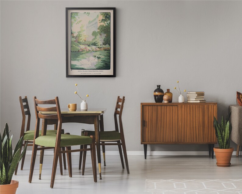May include: A dining room with a wooden table and four chairs. The table has a green tablecloth and a vase of flowers. There is a framed print of a landscape on the wall. A wooden cabinet with sliding doors is in the background.