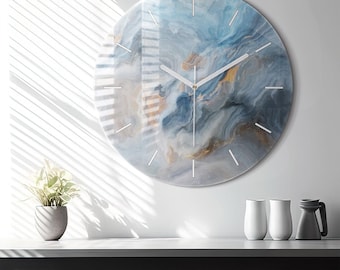 Puede incluir: Un reloj de pared circular con un patrón abstracto de remolinos en tonos azules, grises y dorados. La esfera tiene un acabado liso y brillante con finas marcas horarias blancas y manecillas blancas sencillas, ofreciendo un diseño funcional.