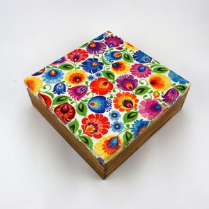 May include: A wooden box with a colourful floral pattern on the lid. The flowers are red, yellow, blue, green, and purple. The box is square and has a wooden base.
