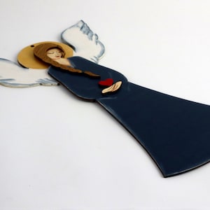 Wooden angel, wall hanging, in navy blue clothes. White wings. Wooden red heart.